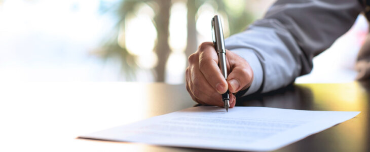 Man in a suit signing a document with a pen