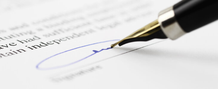 Closeup image of a pen signing a paper